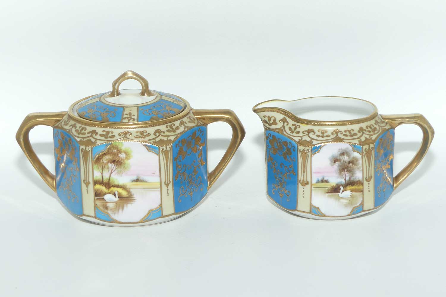 early Noritake Hand Painted and Gilt decorated Blue ground milk and sugar | Hexagonal shape | Lake Scene